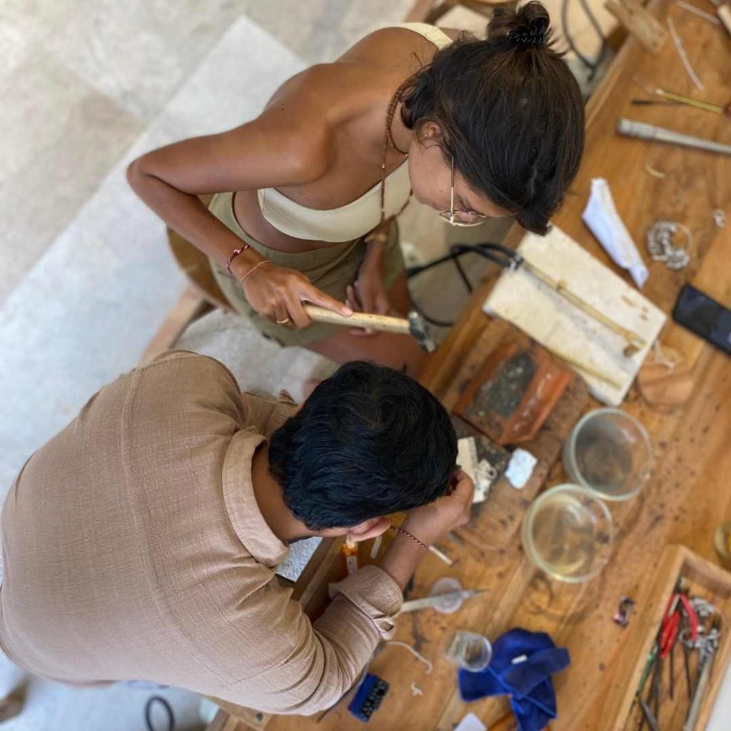 Top view of a guest working with a local artisan during an Uluwatu silver class, learning traditional jewelry-making techniques in Bali.