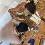 Top view of a guest working with a local artisan during an Uluwatu silver class, learning traditional jewelry-making techniques in Bali.