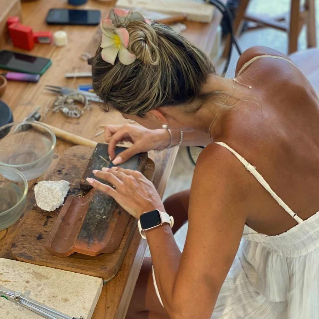 Woman shaping silver jewelry by hand during an Uluwatu silver class, focusing on traditional techniques and creative craftsmanship.