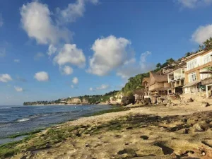 Scenic view of Bingin Beach with rustic beachfront villas and rocky shoreline at low tide a hidden gem among the Best Things to Do in Uluwatu, where visitors can unwind, surf, or take a relaxing Bingin silver class nearby.