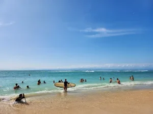 Tourists enjoying the turquoise waters and golden sands of Padang Padang Beach under a clear blue sky a must-visit spot on the list of Best Things to Do in Uluwatu. Perfect for swimming, surfing, or joining a Bingin silver class experience nearby.